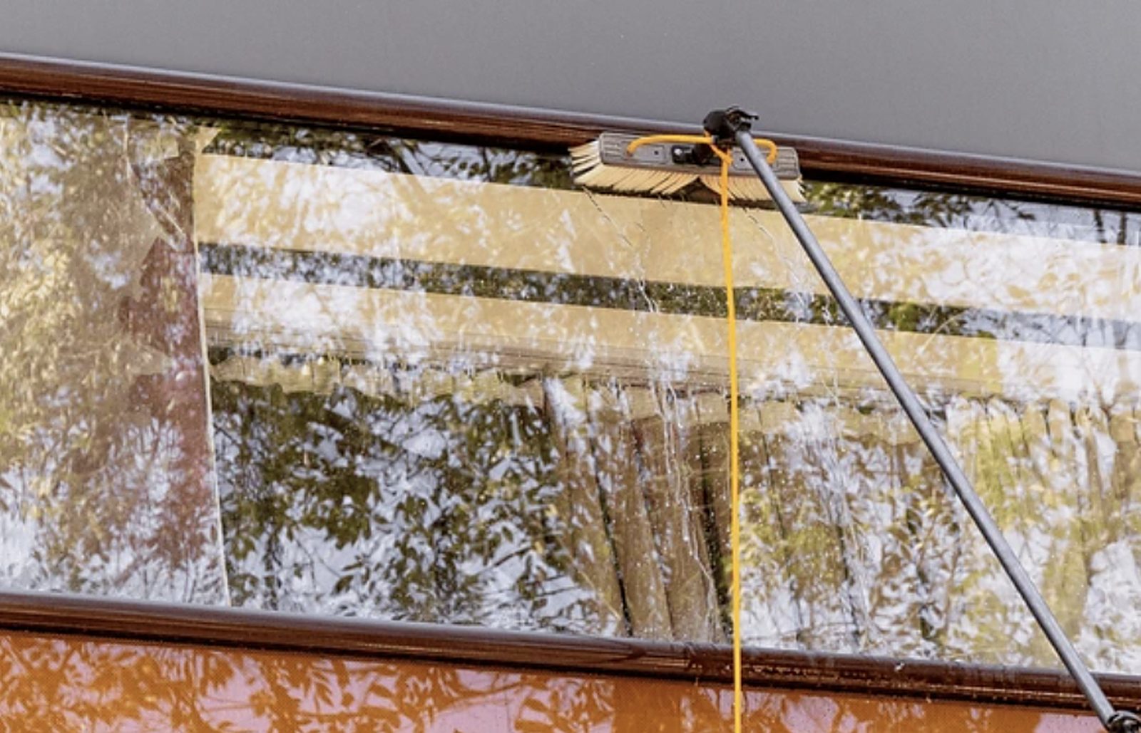 Raam wordt gewassen met een telescoopsteel en waterborstel