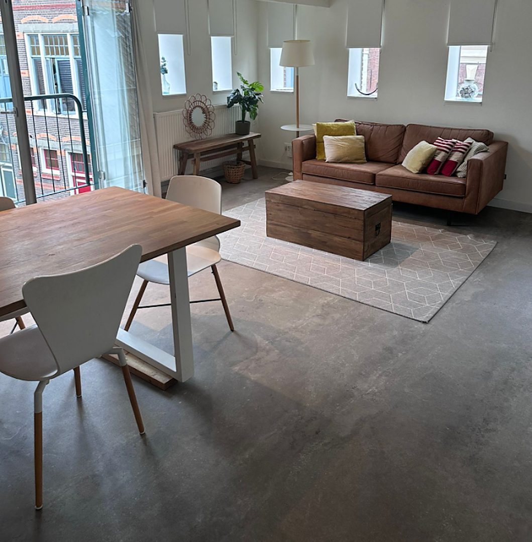 Lichte gemeenschappelijke woonkamer met bank, salontafel en eettafel